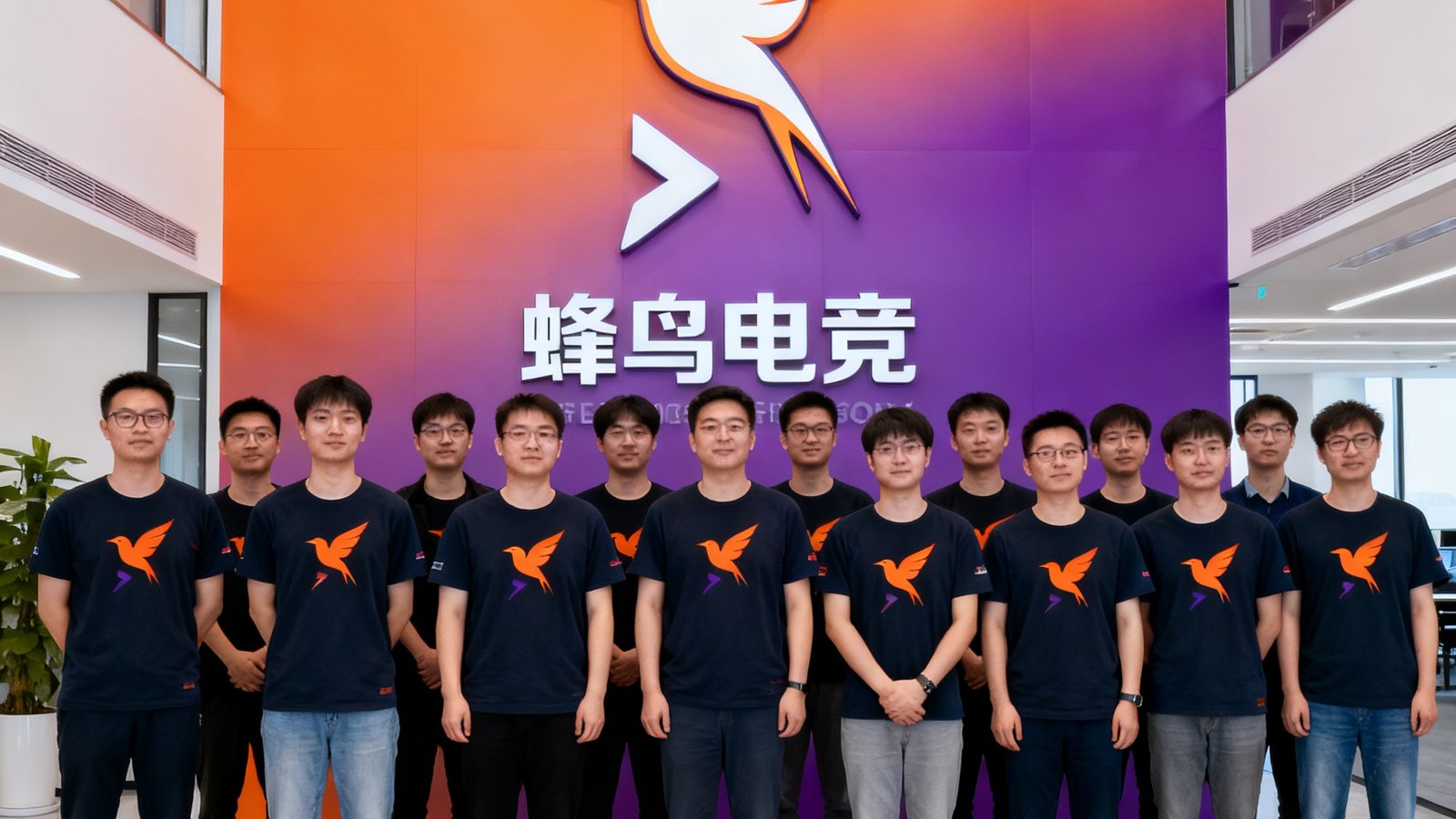 蜂鸟电竞核心团队在上海浦东张江高科技园区总部办公室的合影，约30人站在公司品牌墙前，背景为蜂鸟电竞橙紫渐变的品牌标识，团队成员穿着印有蜂鸟图案的深色文化衫，氛围积极向上。